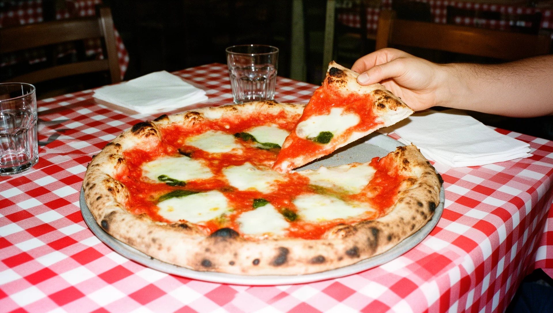 Pizza margherita al centro di una tavola apparecchiata