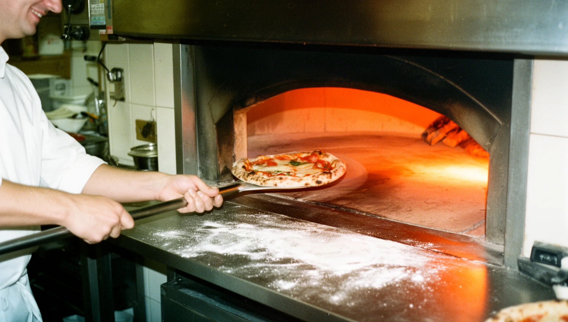 Pizzaiolo al lavoro davanti al forno a legna